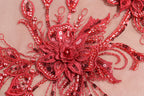 a close-up view of a red, intricately designed flower-like object, adorned with numerous small beads and sequins.