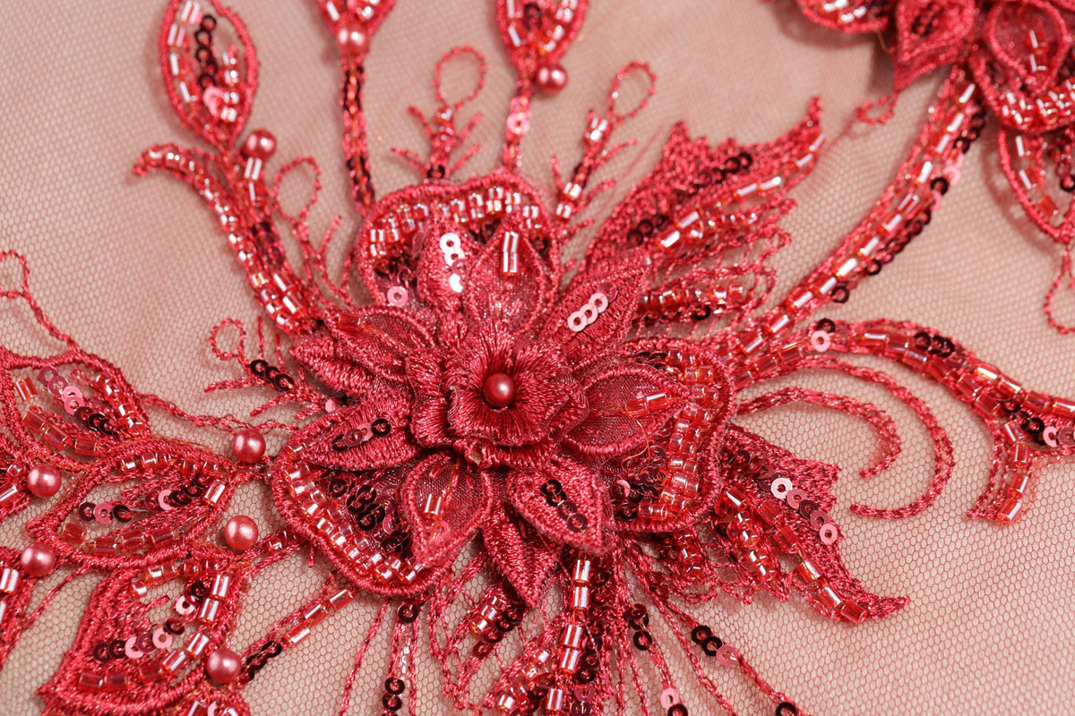 a close-up view of a red, intricately designed flower-like object, adorned with numerous small beads and sequins.