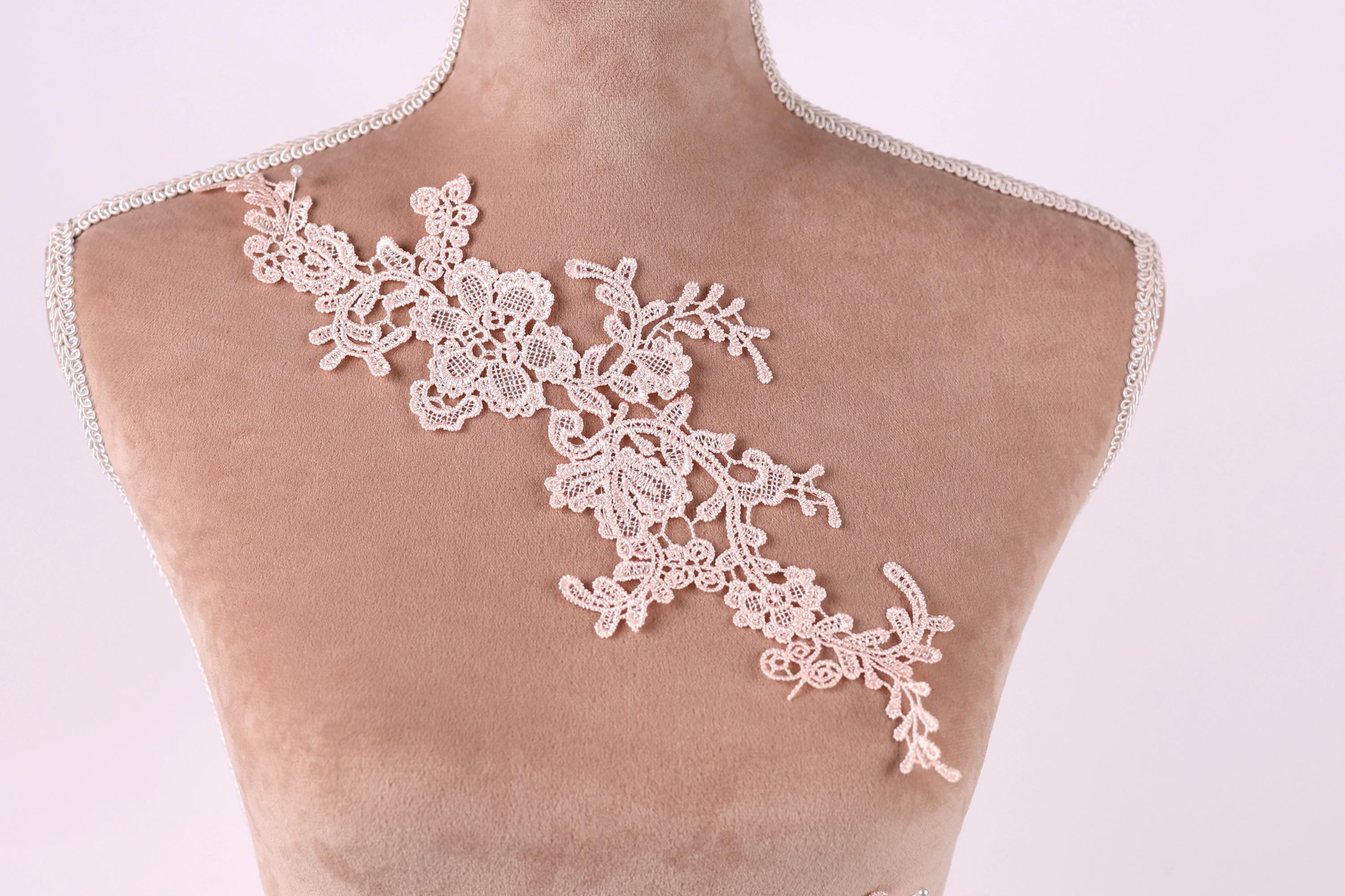 A mannequin torso with a delicate, intricate lace piece sewn onto it.