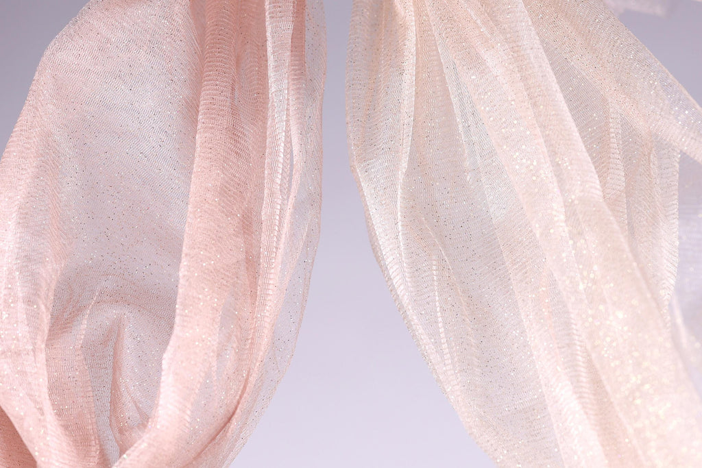 two pieces of light pink fabric, one on the left and one on the right, with a light purple background.