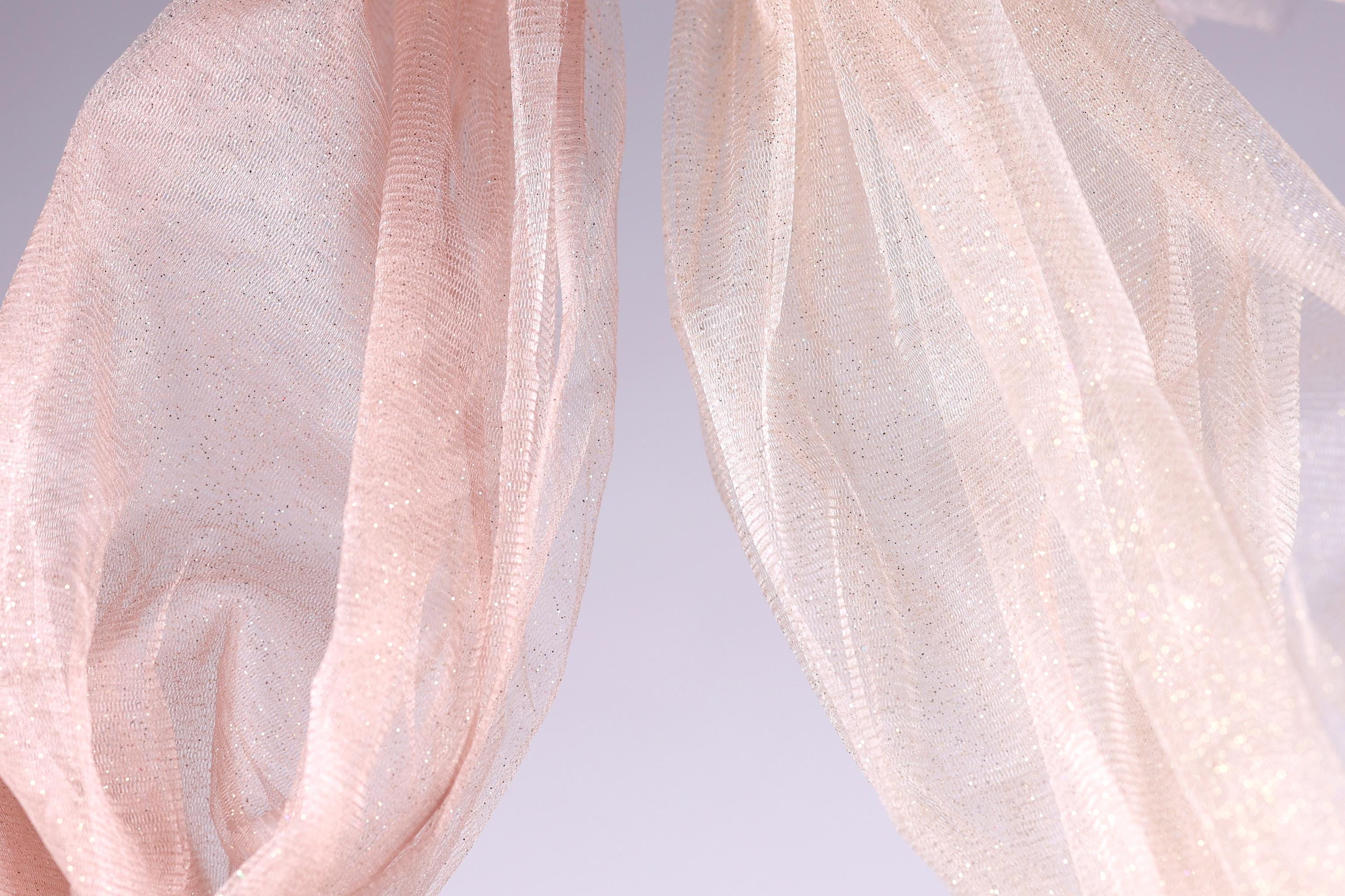 two pieces of light pink fabric, one on the left and one on the right, with a light purple background.