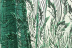 a close-up view of a fabric with a green and black leaf pattern. The fabric appears to be made of a sheer material, with a repeating pattern of green leaves and black lines. The leaves are arranged in a vertical orientation, creating a sense of depth and texture in the image.