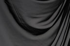 The image is a close-up of a black fabric, possibly a piece of clothing or a textile. The fabric appears to be wrinkled and has a textured surface, giving it a somewhat rough appearance.