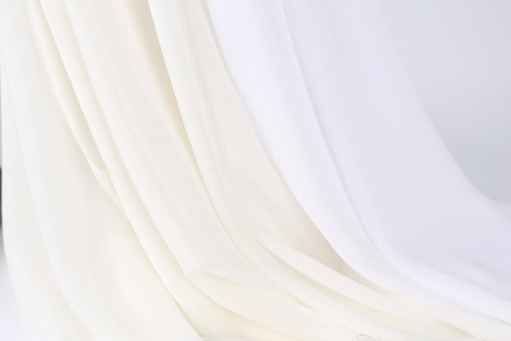The image is a close-up of a white fabric, possibly a sheer or sheer-like material, with a soft, flowing texture.