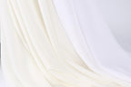 The image is a close-up of a white fabric, possibly a sheer or sheer-like material, with a soft, flowing texture.