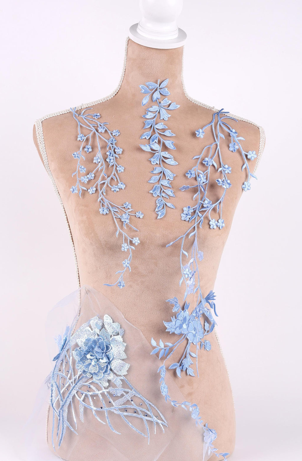 A mannequin wearing a dress with delicate blue floral embroidery on the bust and waist area.