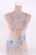 A mannequin wearing a dress with delicate blue floral embroidery on the bust and waist area.