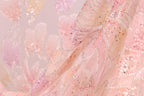 The image is a close-up of a fabric with a pink and white floral pattern, featuring small sequins or beads that add texture and sparkle to the fabric.
