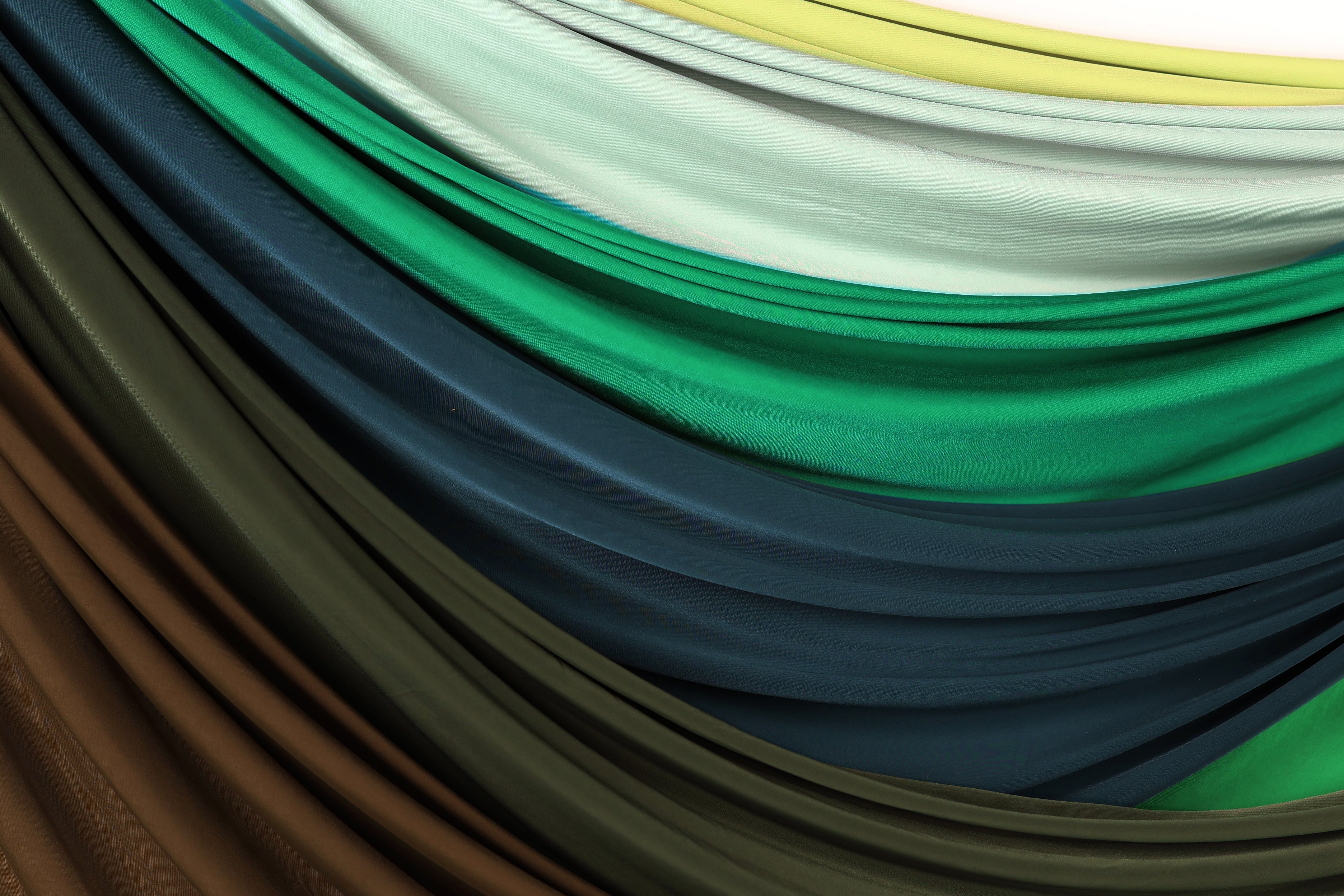 a variety of colorful fabrics, including green, blue, brown, and white, arranged in a visually appealing manner.