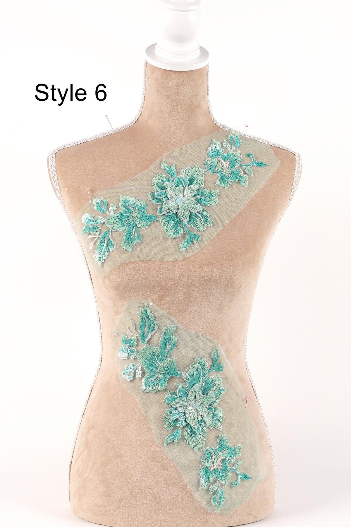 A mannequin with a beige body and a white head, wearing a light green floral embroidered on its torso.