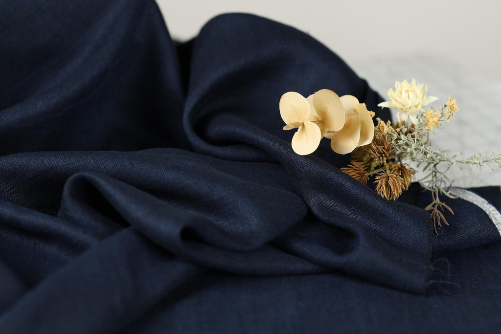 a close-up view of a dark blue fabric with a delicate arrangement of yellow flowers resting on it.