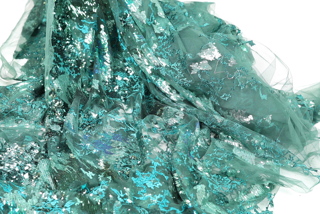 a close-up view of a fabric with a green and silver metallic texture, creating a shimmering and sparkling effect.