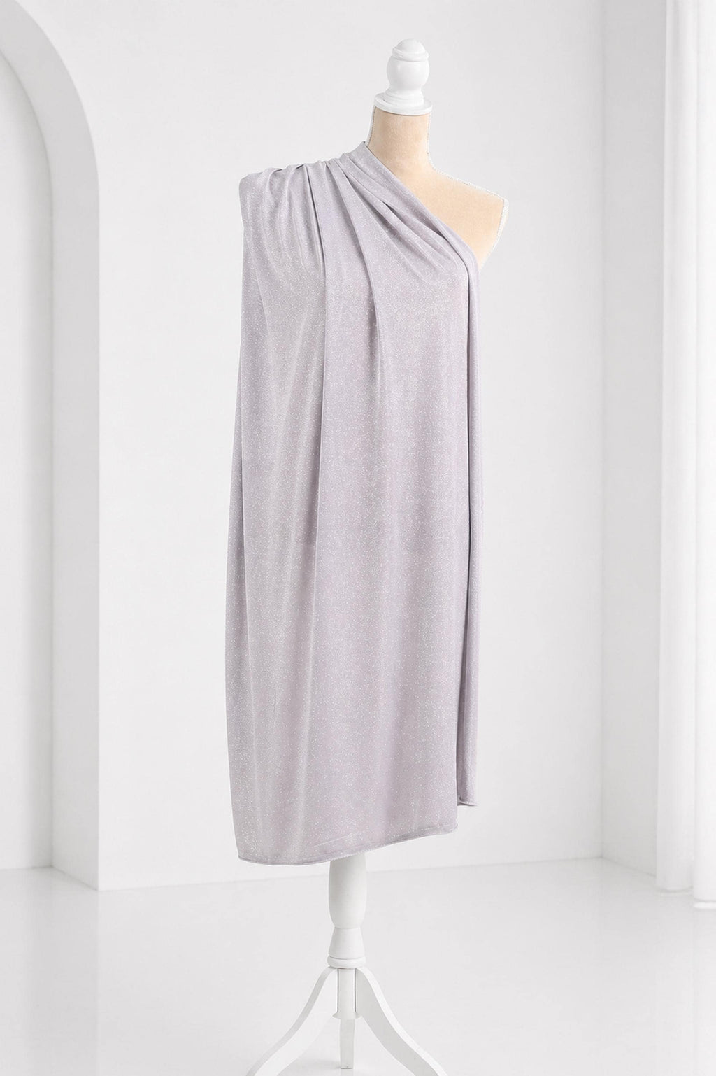 A mannequin wearing a gray draped garment stands on a white stand against a white background.