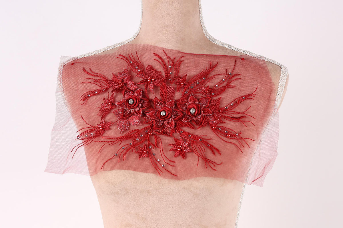 a mannequin torso with a red, floral-patterned fabric covering it. The fabric appears to be made of sheer material and has a decorative, embroidered design.