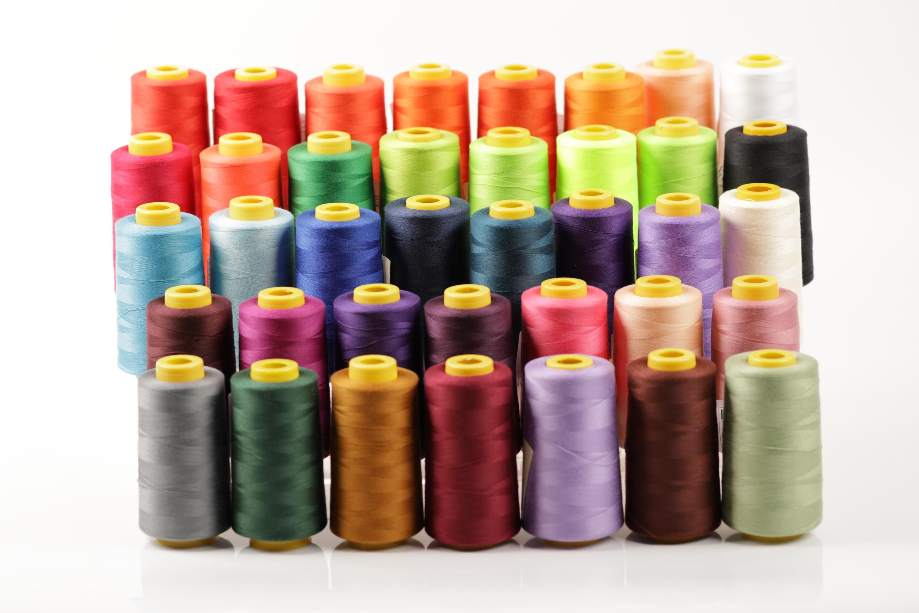 a collection of colorful spools of thread arranged in rows, showcasing a variety of colors and patterns.
