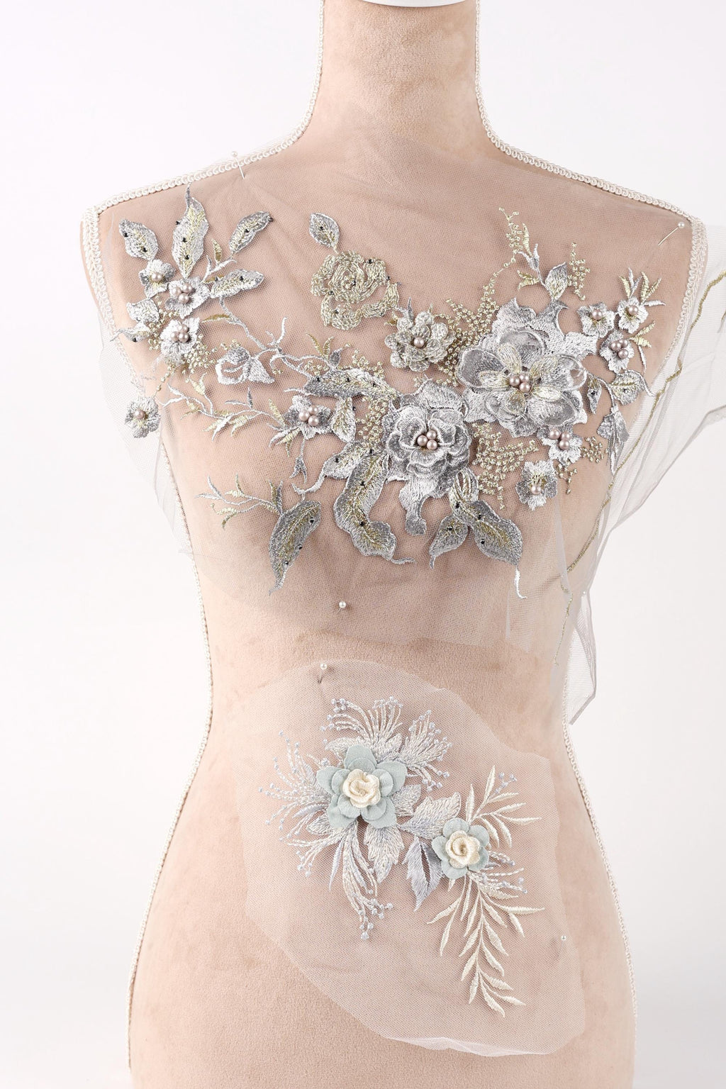 A mannequin with a beige body and a white dress top adorned with intricate floral embroidery.