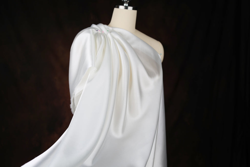 A white, flowing dress on a mannequin against a dark background.