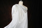 A white, flowing dress on a mannequin against a dark background.