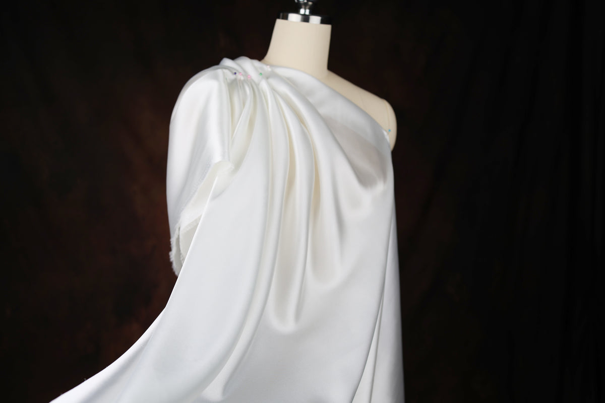 A white, flowing dress on a mannequin against a dark background.