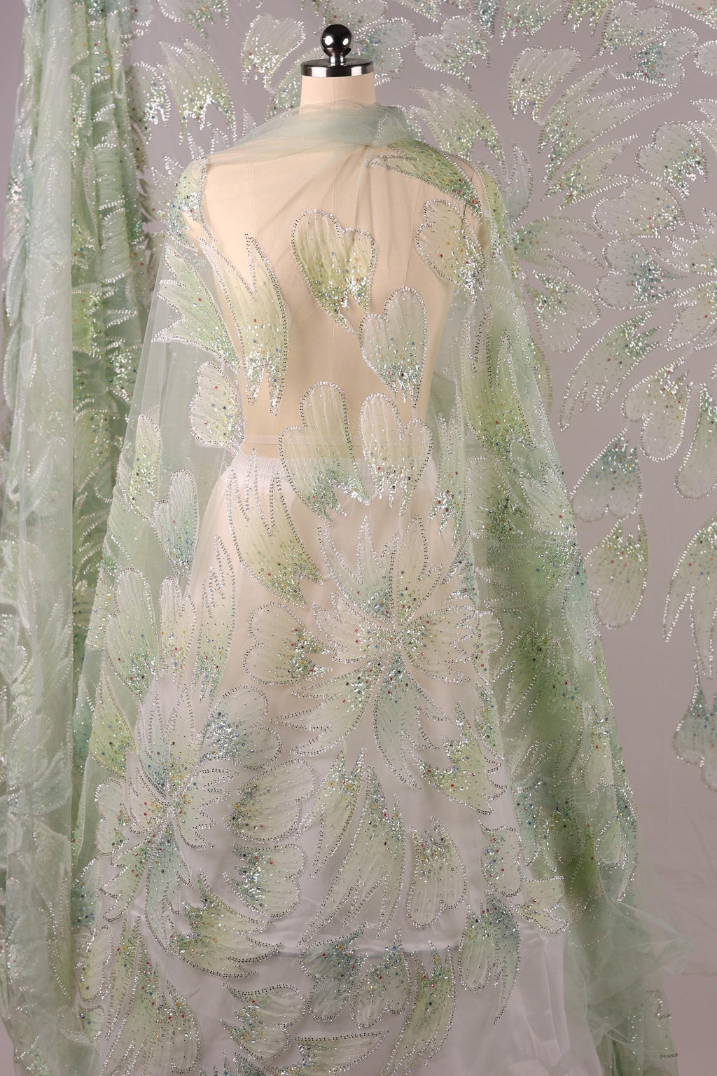 a fabric with a floral pattern, including white and green flowers, and a sheer, transparent overlay.