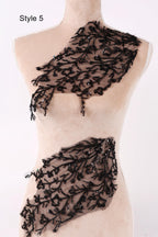 A mannequin wearing a beige dress with black lace and beaded details on the neckline and waist area.