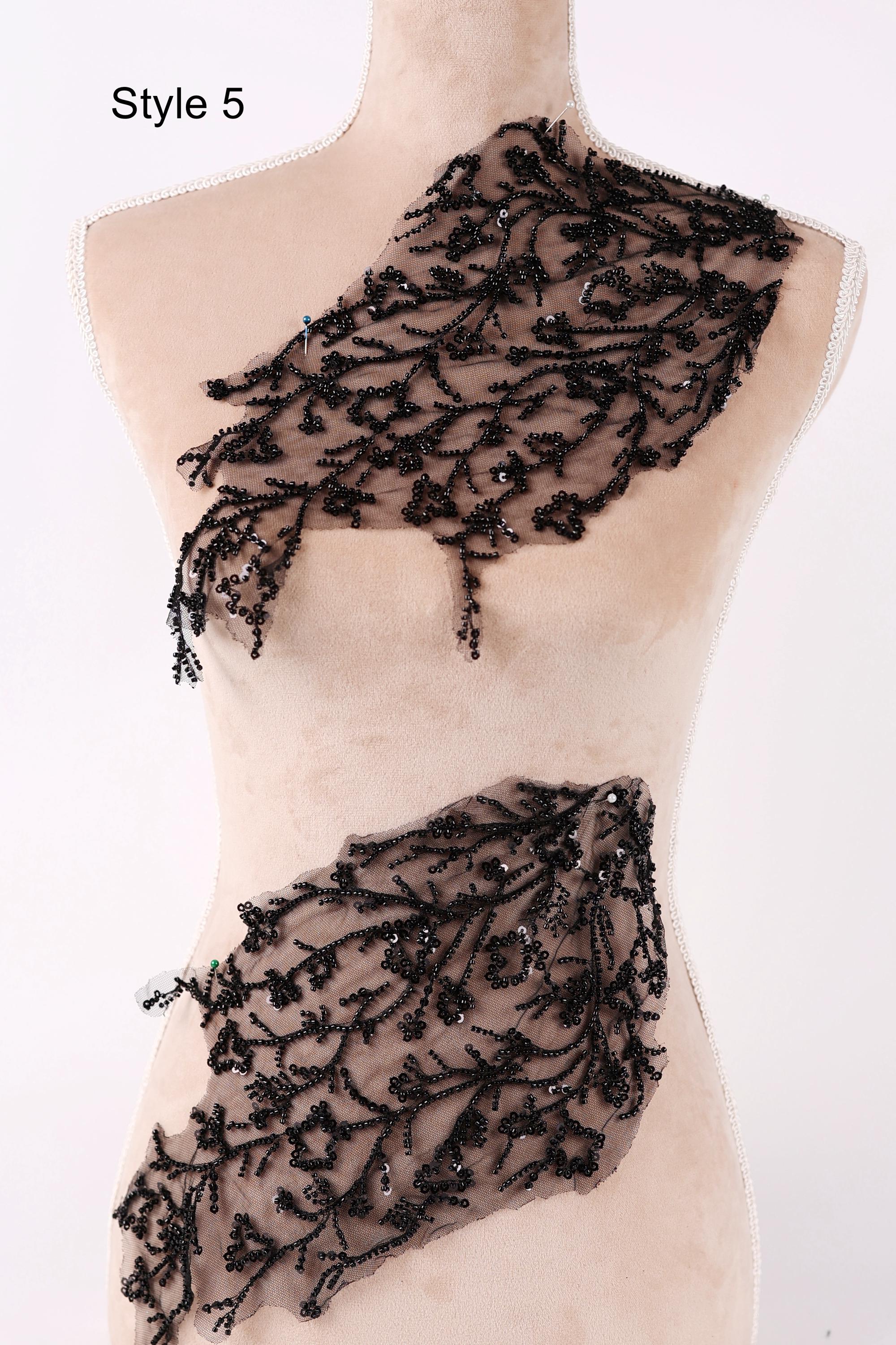 A mannequin wearing a beige dress with black lace and beaded details on the neckline and waist area.