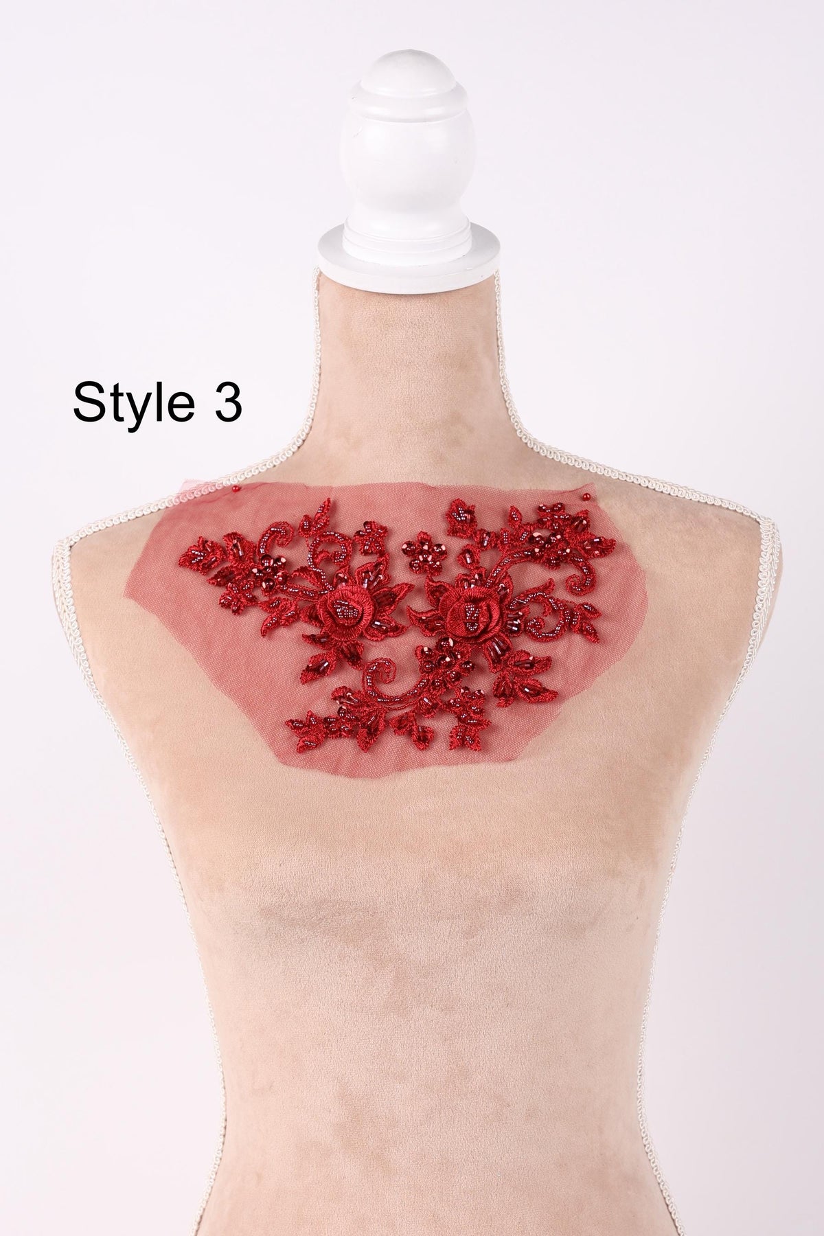 A mannequin head with a red floral lace overlay on the bust area.