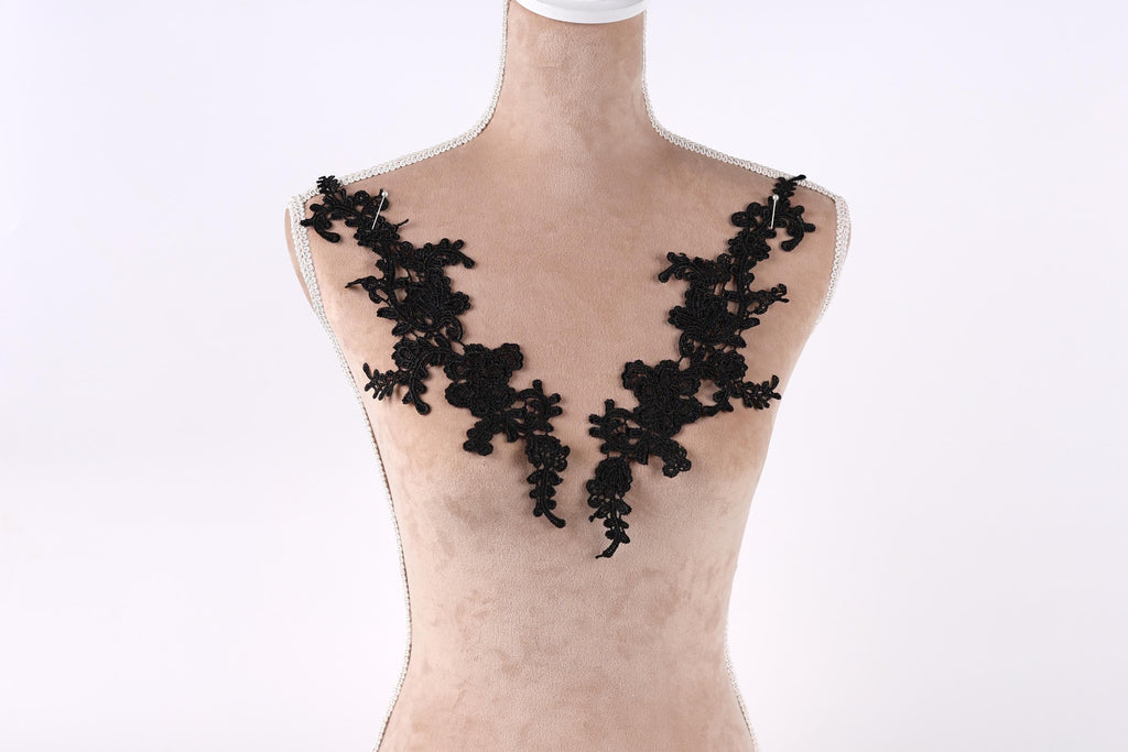 A mannequin with black lace or floral embroidery on its shoulders.