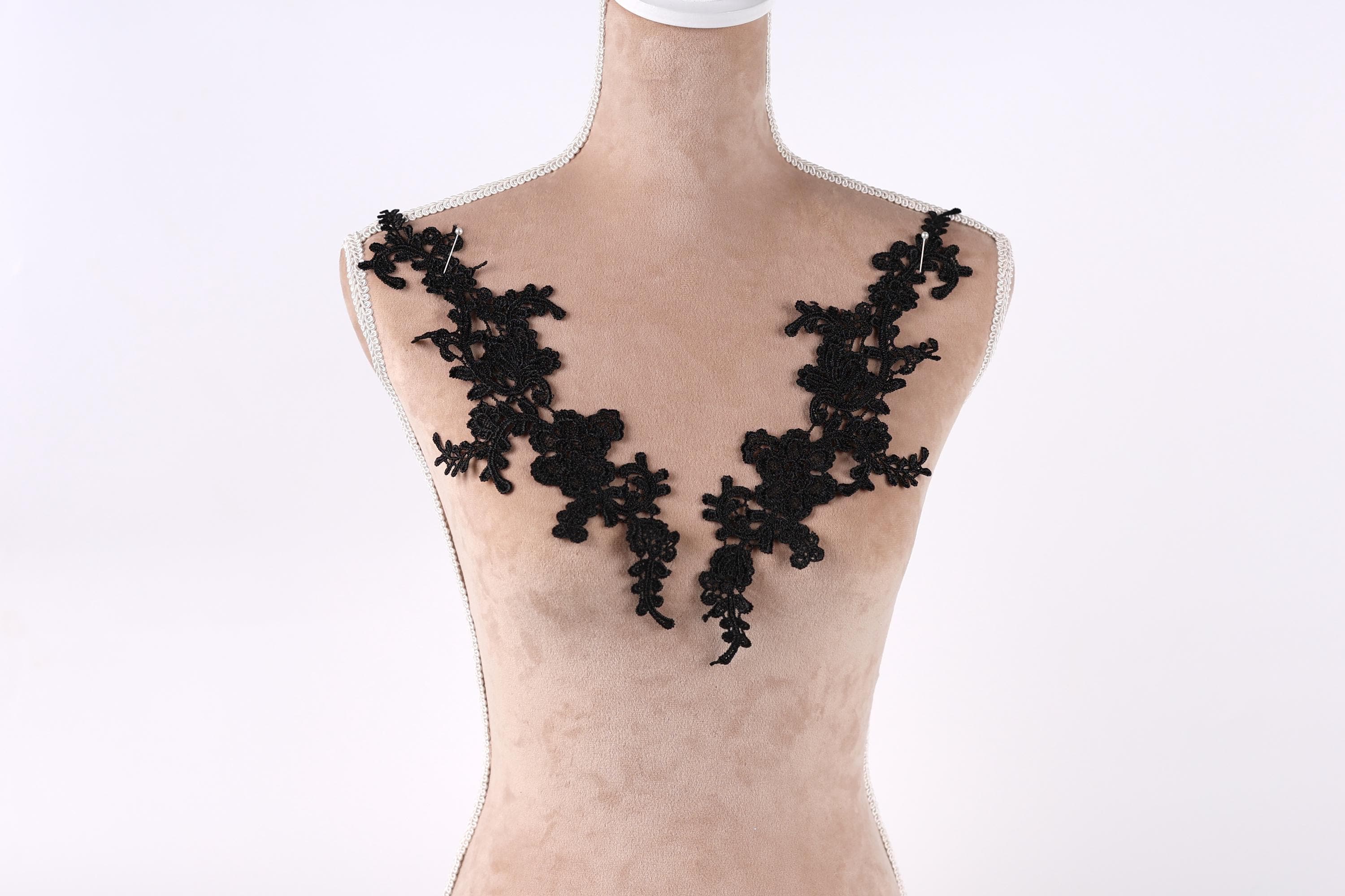 A mannequin with black lace or floral embroidery on its shoulders.
