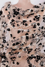a close-up view of a sheer fabric with a black floral pattern. The fabric appears to be made of sheer material, giving it a delicate and airy appearance. The black flowers are arranged in a way that covers the entire fabric, creating a visually striking contrast against the lighter background.