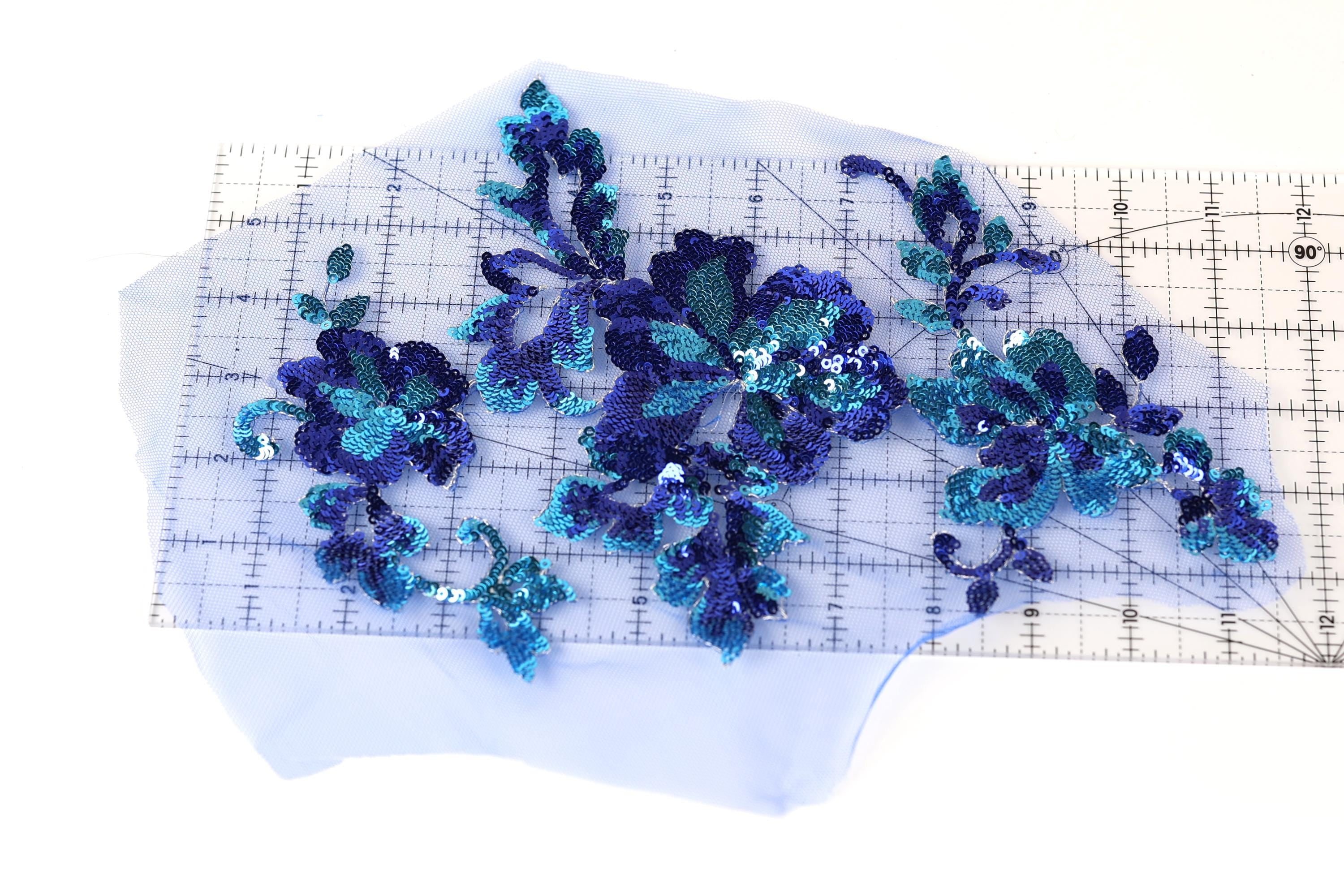 a clear measuring tape with blue sequin flowers placed on it.