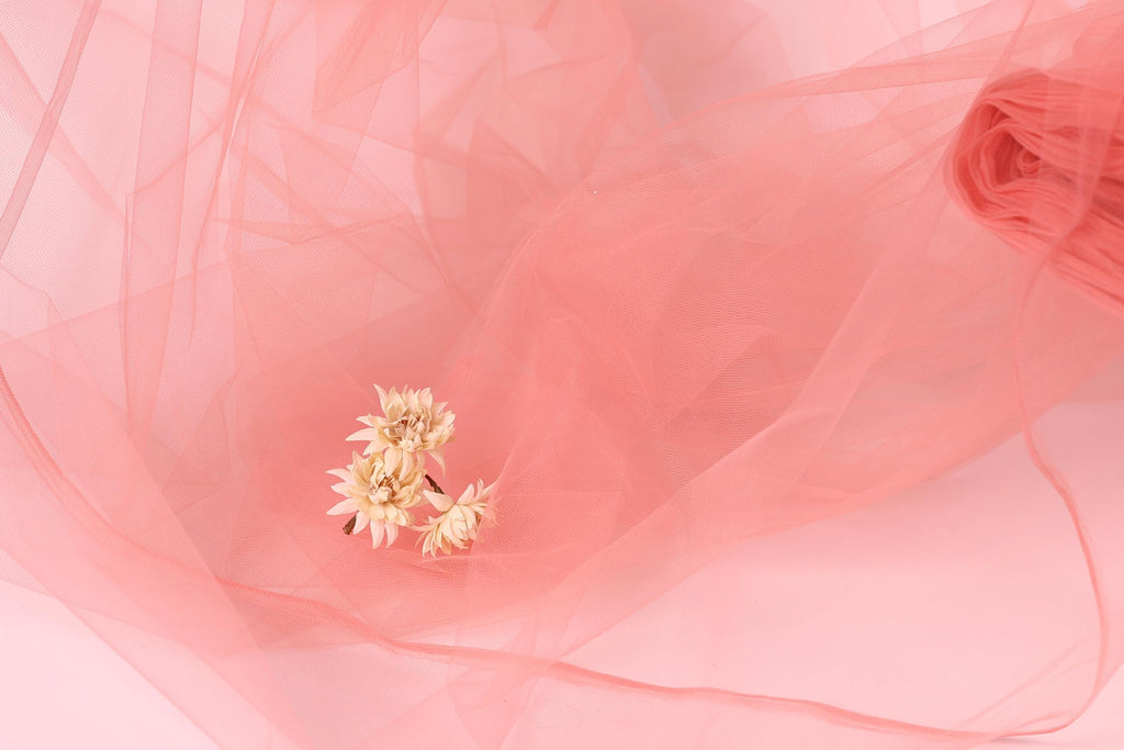 a delicate arrangement of small white flowers resting on a soft pink background.