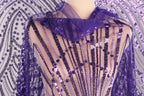 a mannequin wearing a purple sequin shawl with a sheer overlay.