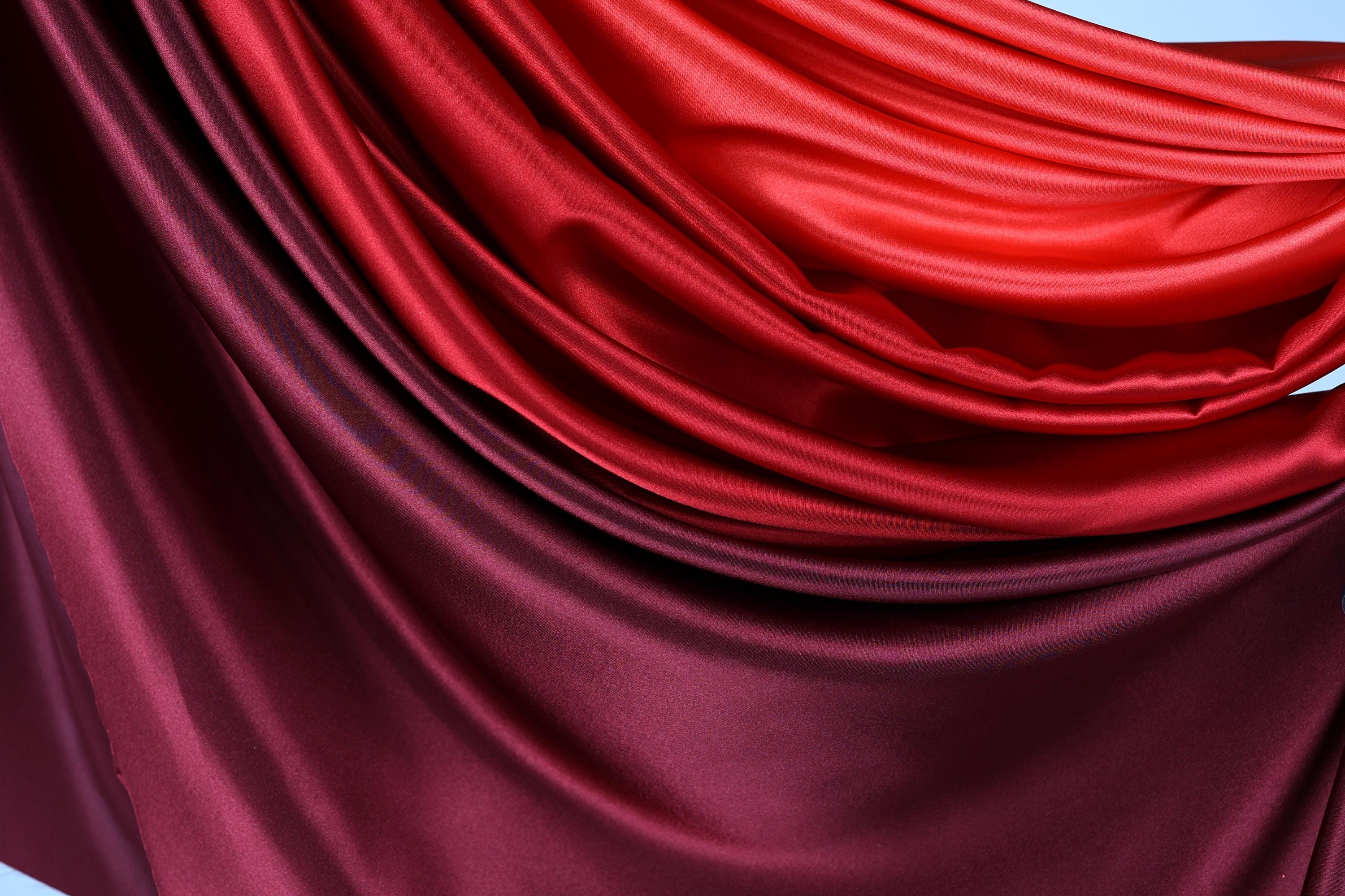 a close-up view of a fabric with a gradient of red and maroon colors, creating a visually striking and textured appearance.