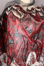 a close-up view of a fabric with a striking red and black pattern, adorned with sequins and lace-like details. The fabric appears to be a sheer material, with a black lace-like design on the edges and a red sequin-covered area. The overall composition of the image is visually captivating and intricate, showcasing the craftsmanship and artistry involved in creating such a fabric.