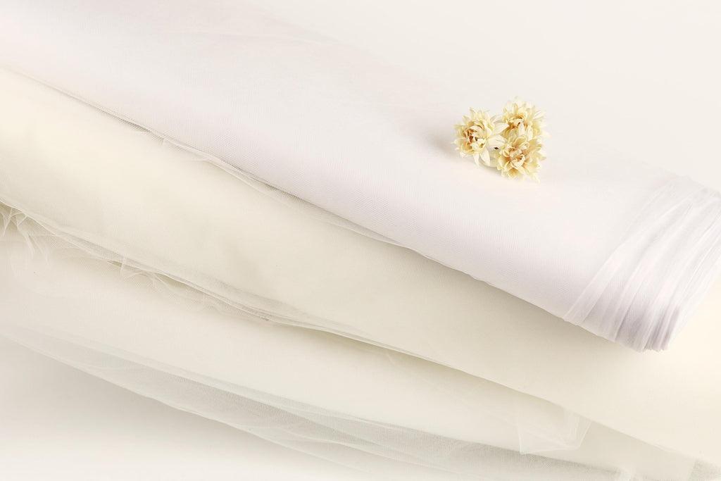 a white fabric, possibly a sheer or sheer lace, with a small yellow flower resting on top of it.