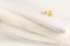 a white fabric, possibly a sheer or sheer lace, with a small yellow flower resting on top of it.