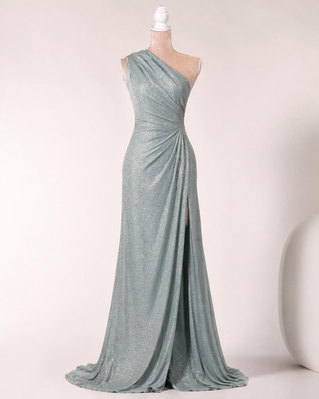 A long, one-shoulder, form-fitting dress with a shimmering, metallic sheen. The dress has a high slit on the side and a flowing, draped skirt.