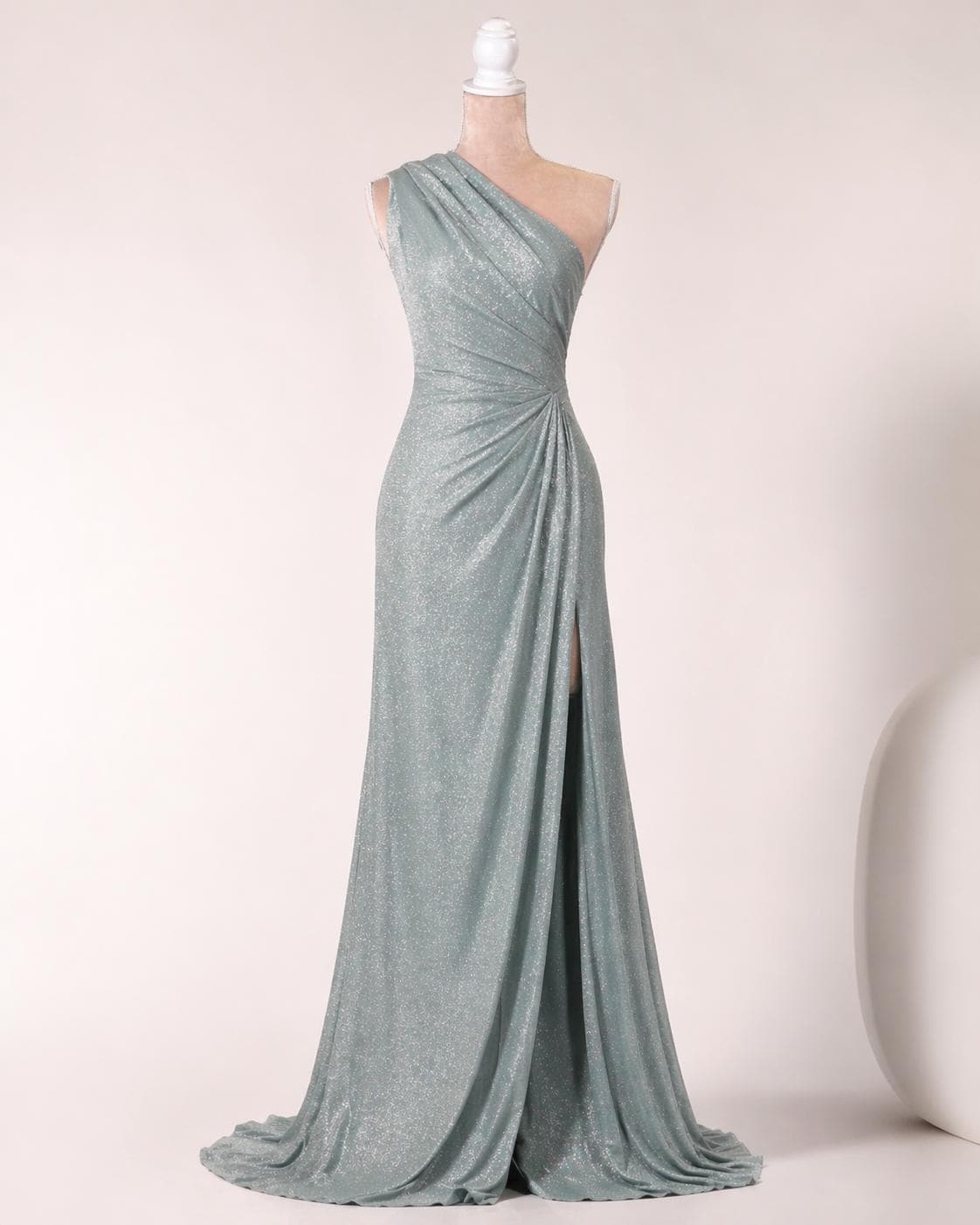 A long, one-shoulder, form-fitting dress with a shimmering, metallic sheen. The dress has a high slit on the side and a flowing, draped skirt.