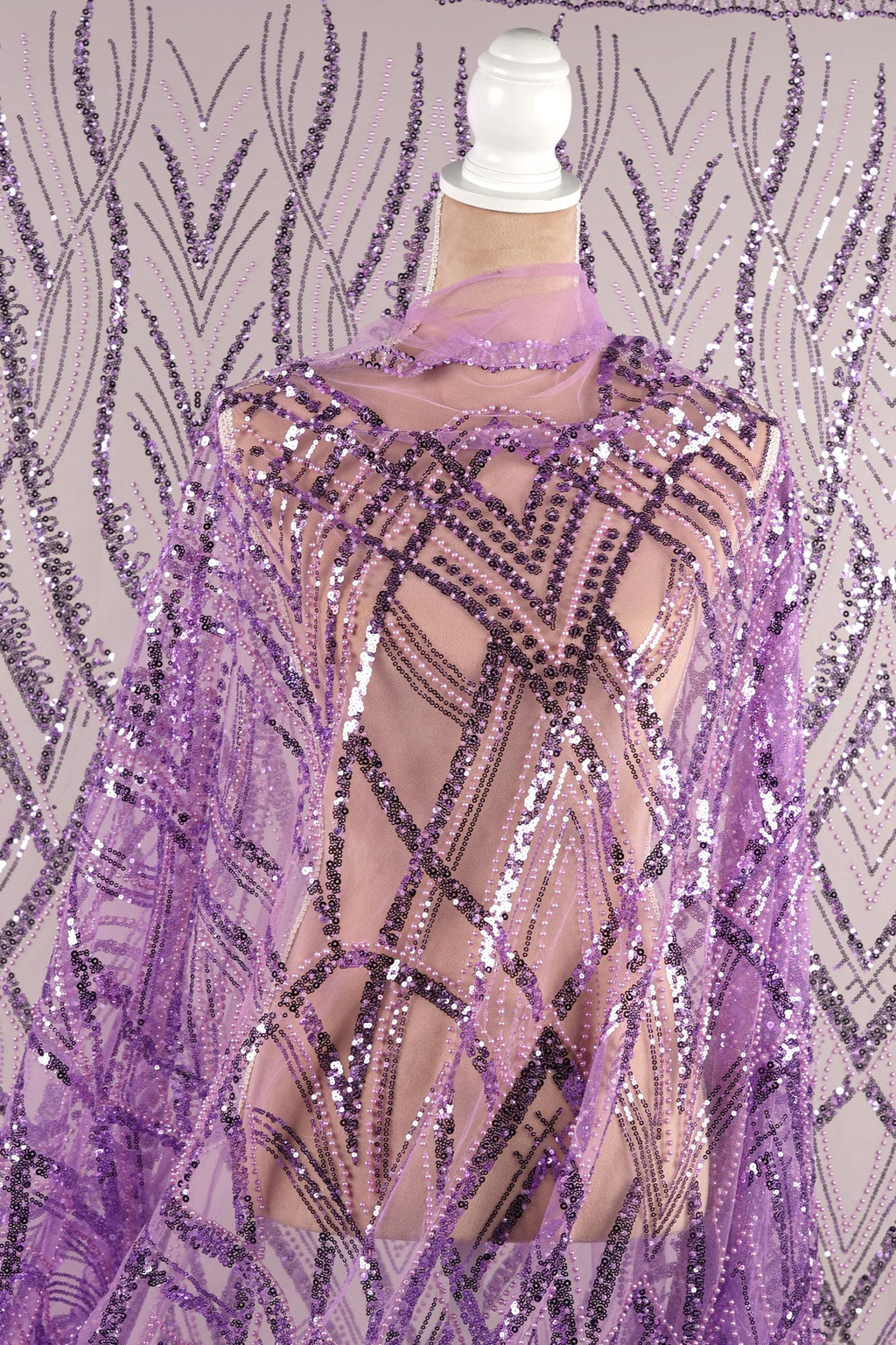 a mannequin wearing a purple sequin shawl with a geometric pattern.