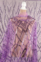 a mannequin wearing a purple sequin shawl with a geometric pattern.