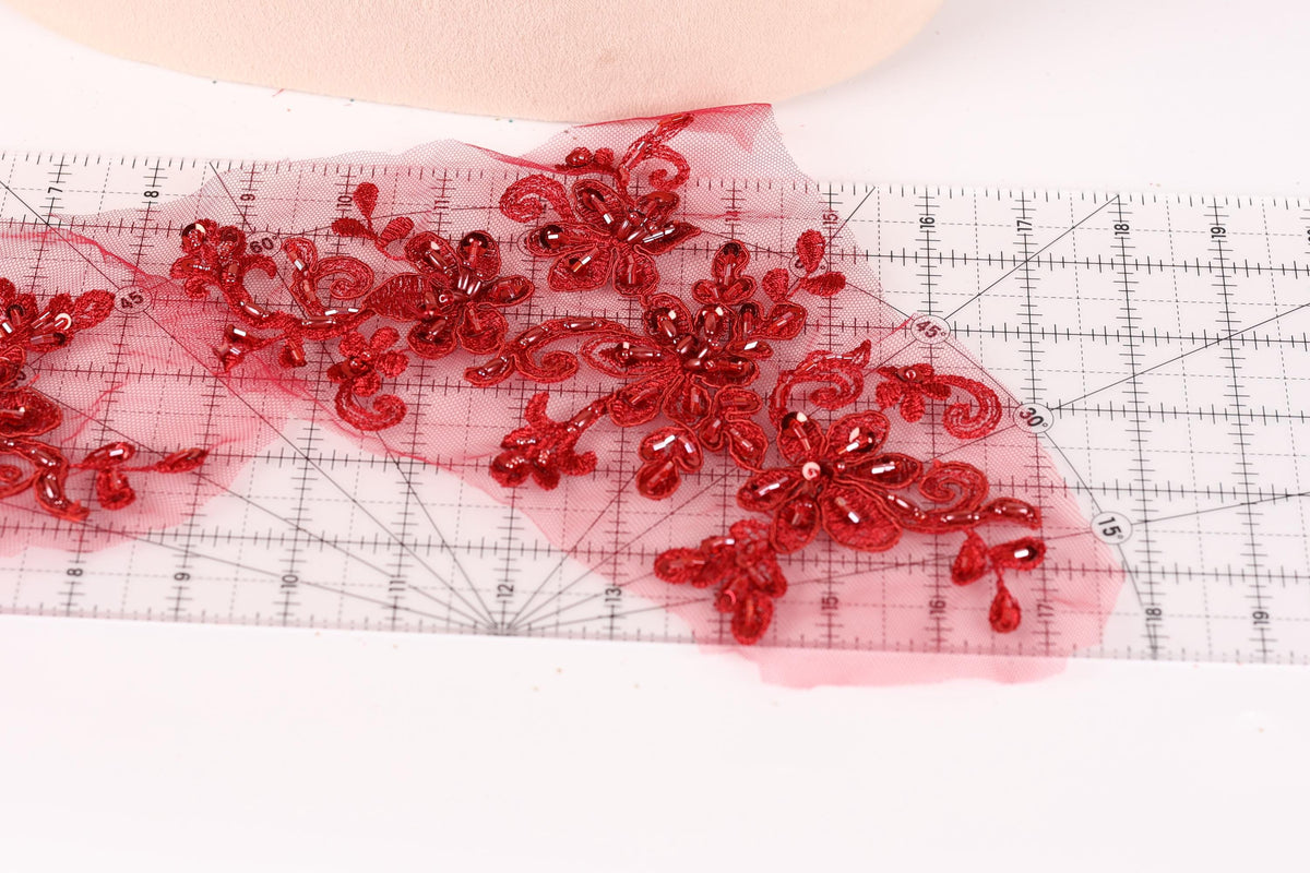 a close-up view of a red floral pattern on a transparent surface, with a ruler visible in the background.
