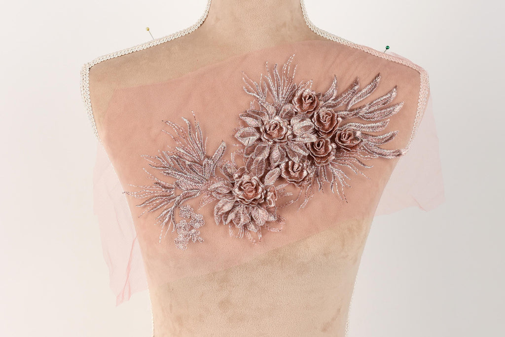 a mannequin with a pink fabric adorned with a floral design, including roses and leaves.