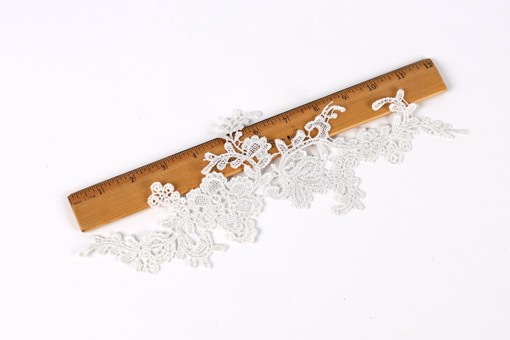a close-up view of a wooden ruler with a lace-like pattern on it, placed on a white background.