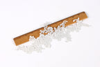 a close-up view of a wooden ruler with a lace-like pattern on it, placed on a white background.