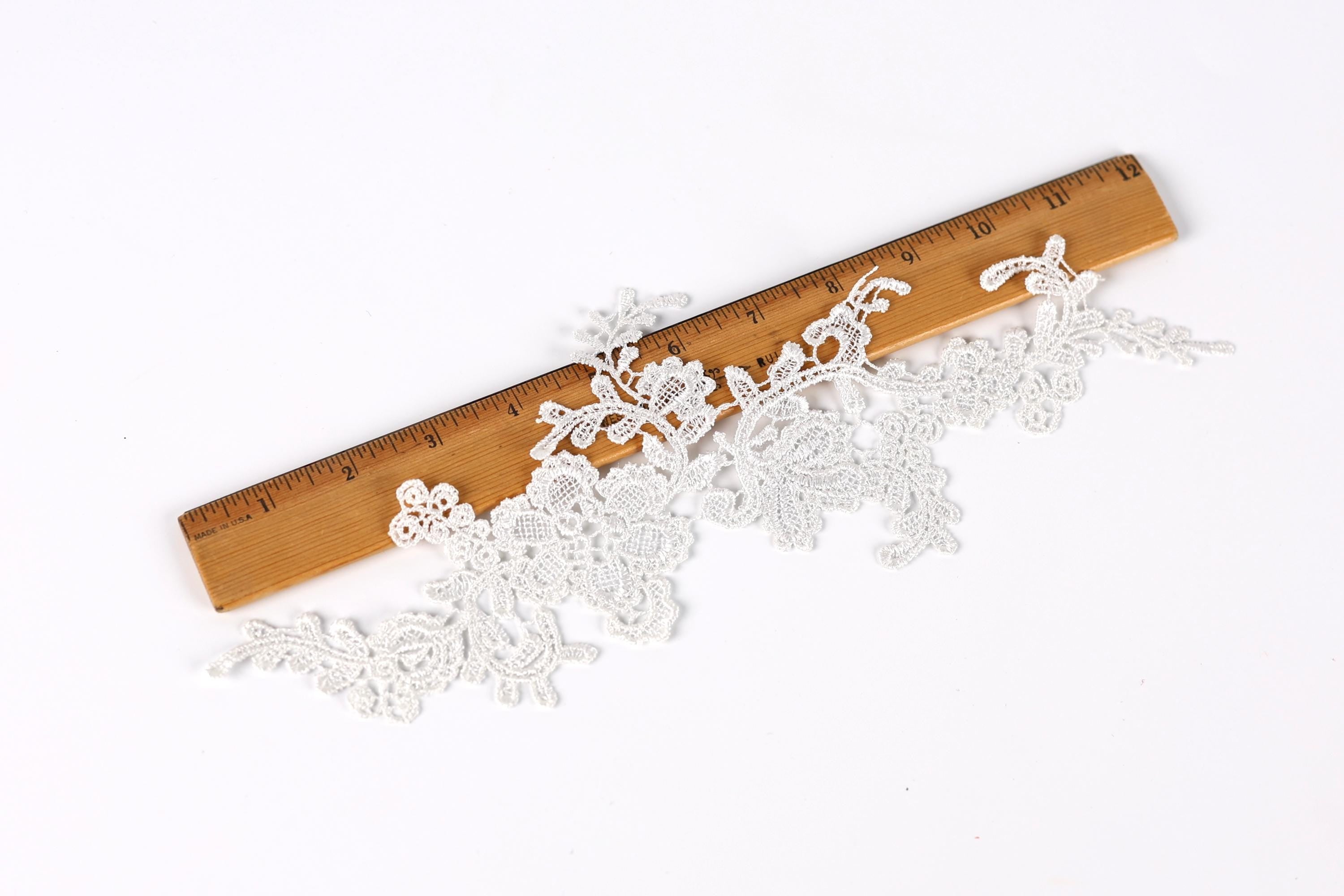 a close-up view of a wooden ruler with a lace-like pattern on it, placed on a white background.