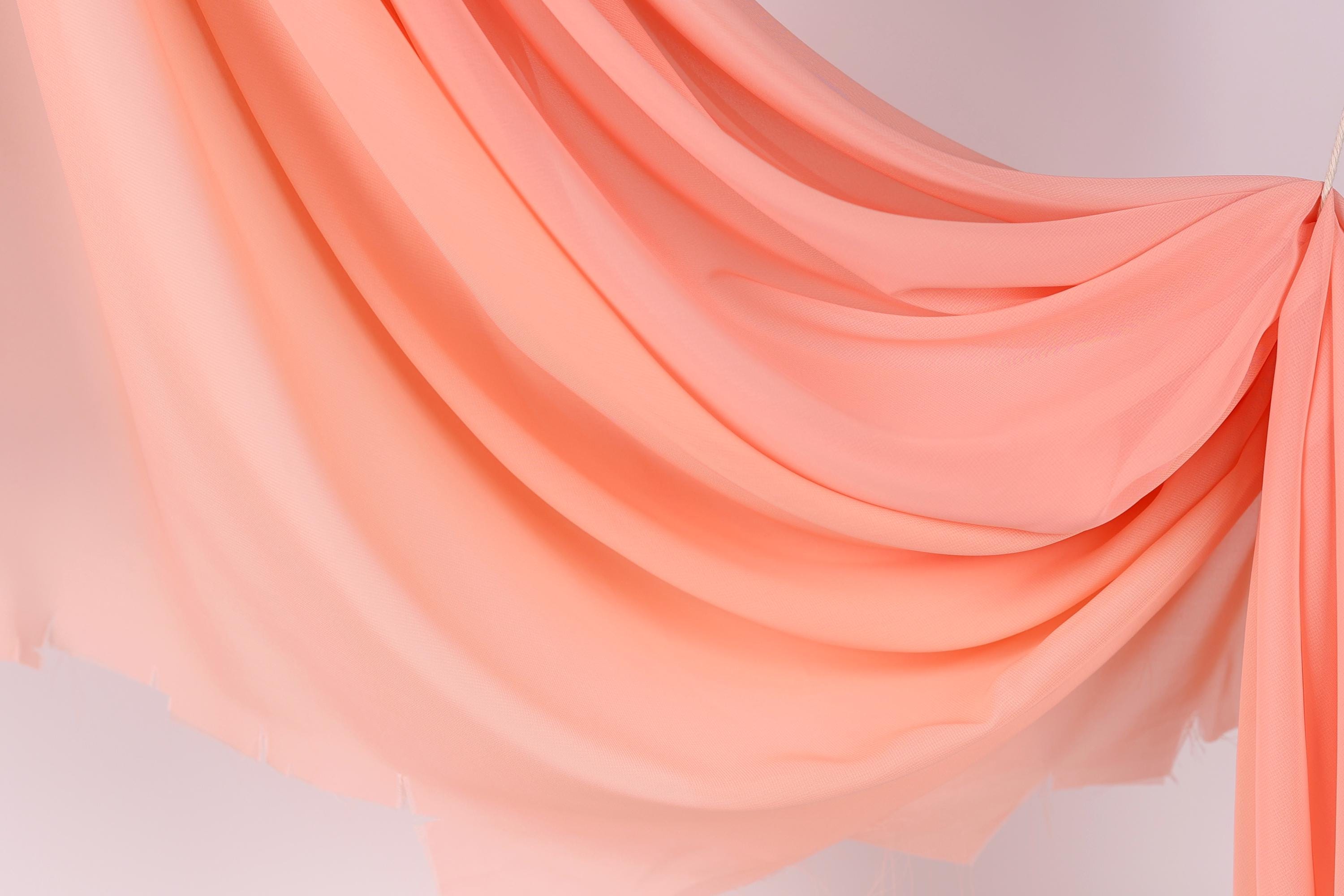 a flowing, draped fabric in a soft, pastel pink color.