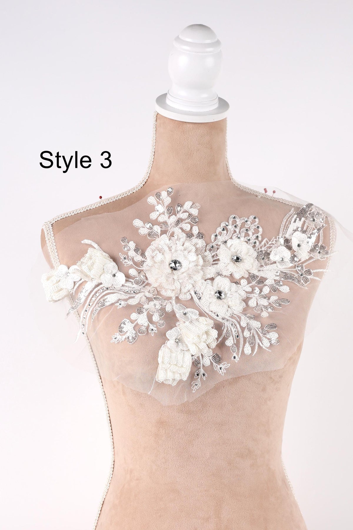 A mannequin with a decorative white lace bodice featuring a floral pattern.