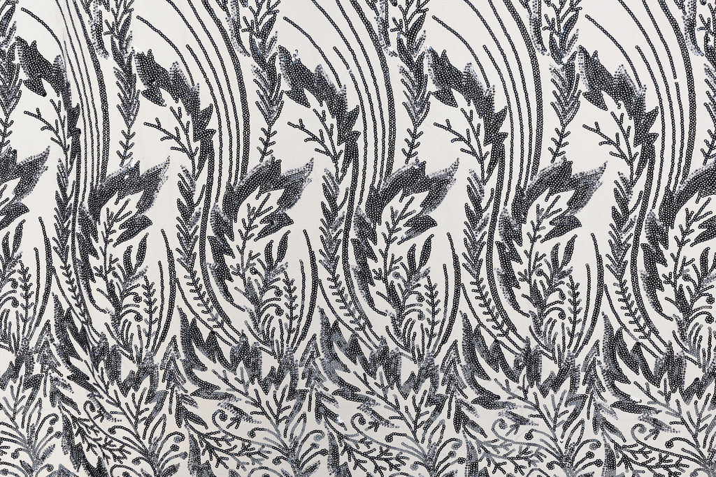 a repeating pattern of black and white floral designs on a fabric surface.