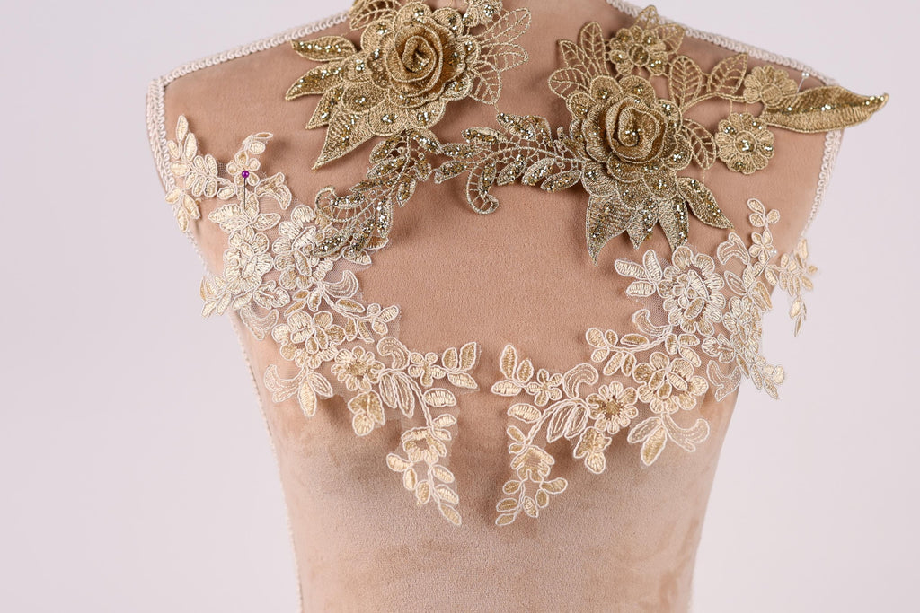 A mannequin wearing a dress with intricate gold lace and floral embroidery on the shoulders and back.